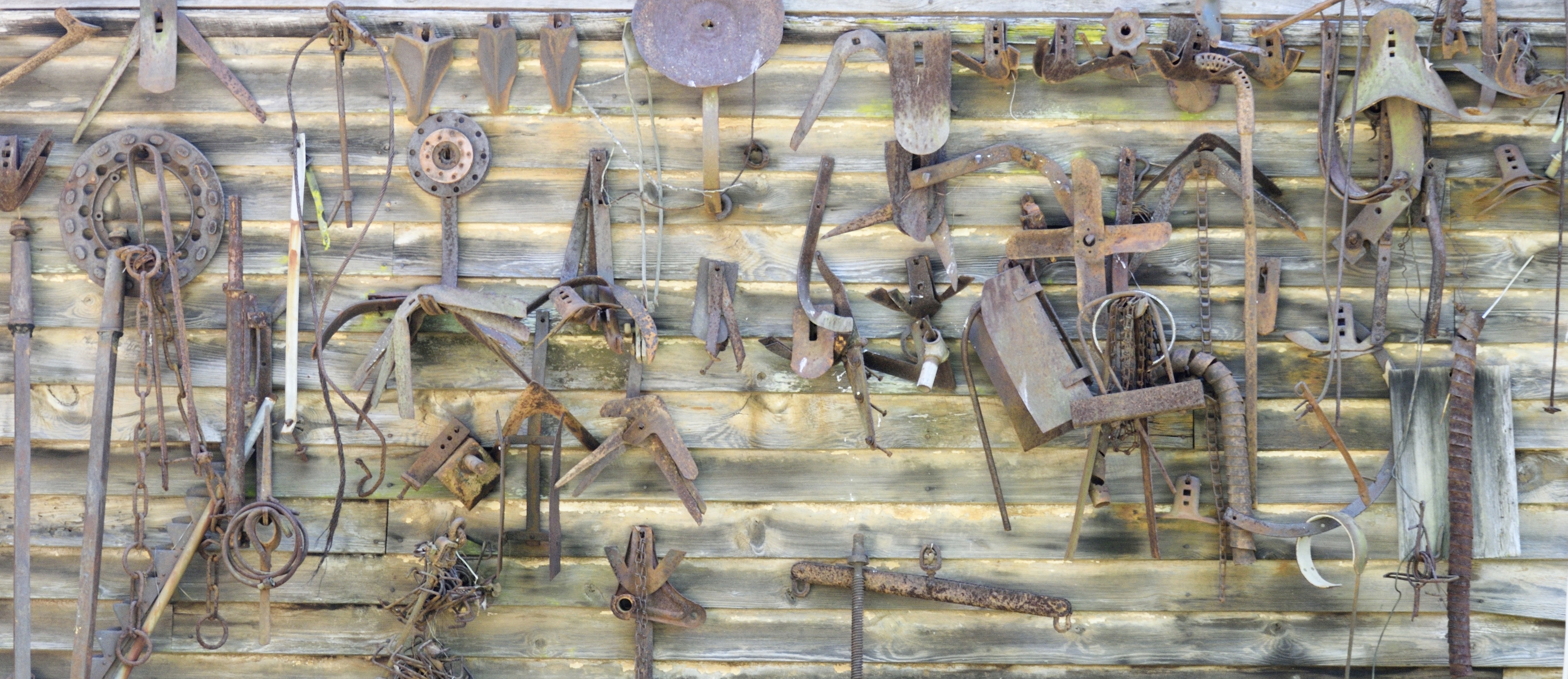 an old barn wall with rusty tools hanging on it