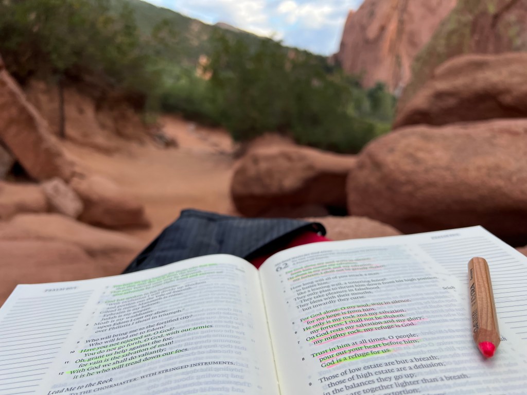 looking out through the red rocks of 
Garden of the Gods with an open Bible and Psalm 62 highlighted
